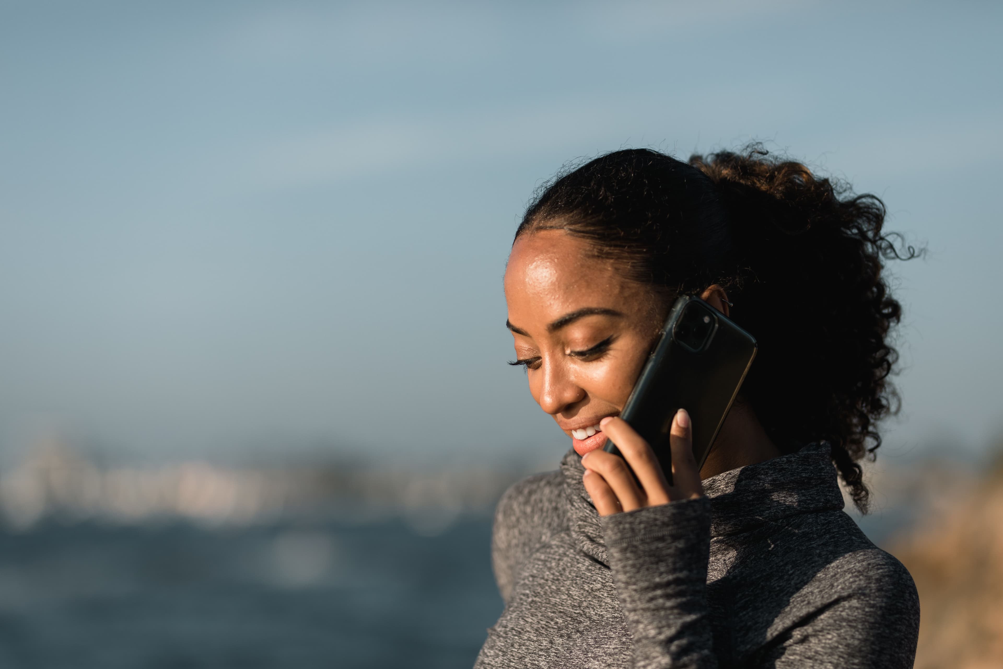 Woman speaking on a phone outdoors while reviewing her benefits